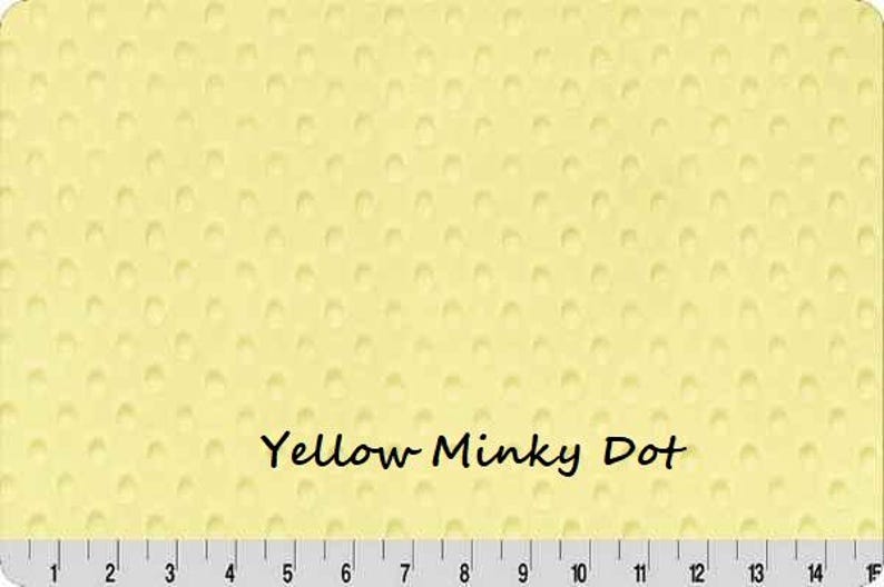 May include: A light yellow fabric with a textured dot pattern. The words "Yellow Minky Dot" are printed in black. A ruler is at the bottom of the image, with measurements in inches.