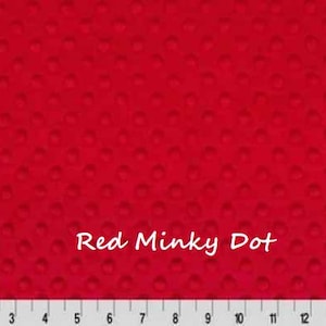 May include: A vibrant red minky fabric featuring a raised, embossed dot pattern across the entire surface. The text "Red Minky Dot" is printed in white in the center. A white ruler at the bottom shows measurements in inches from 1 to 15.