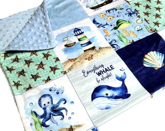 Puede incluir: Una manta de patchwork para bebé con tela minky de color azul claro con hoyuelos en un lado y varios cuadrados de temática náutica en el otro, incluyendo ilustraciones de un faro, estrellas de mar, un pulpo y una ballena con el texto Everything WHALE be alright!