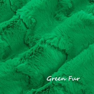May include: A vibrant green faux fur fabric with a dense, soft texture and a repeating wavy pattern. The material features a plush, thick pile that creates deep shadows and highlights across the surface. The text Green Fur is visible.