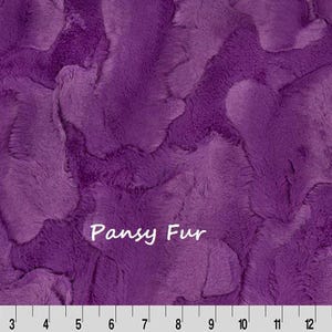 Pu&ograve; includere: Primo piano di un tessuto di peluche strutturato in tonalit&agrave; viola. Il tessuto ha un aspetto morbido, simile alla pelliccia, con un motivo ondulato. Il testo "Pansy Fur" &egrave; visualizzato in bianco. Un righello &egrave; in basso.