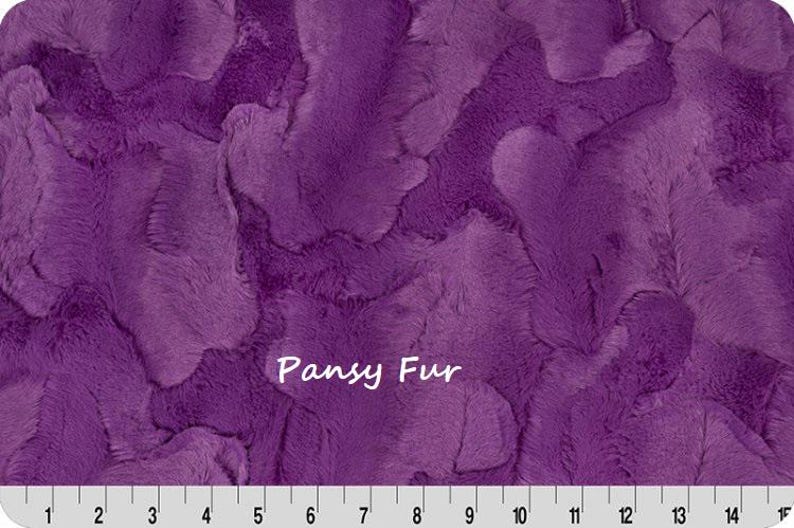 Pu&ograve; includere: Primo piano di un tessuto di peluche strutturato in tonalit&agrave; viola. Il tessuto ha un aspetto morbido, simile alla pelliccia, con un motivo ondulato. Il testo "Pansy Fur" &egrave; visualizzato in bianco. Un righello &egrave; in basso.