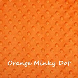 May include: Orange minky dot fabric with a textured, raised dot pattern. The fabric is soft and plush.