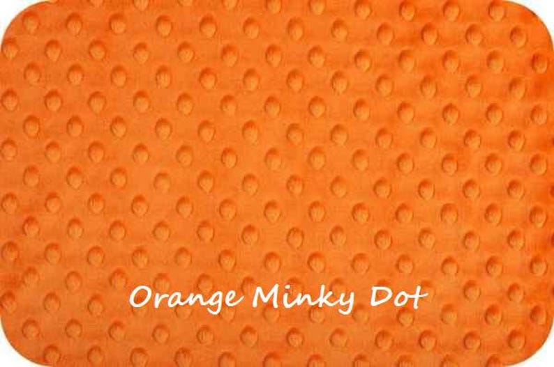 May include: Orange minky dot fabric with a textured, raised dot pattern. The fabric is soft and plush.