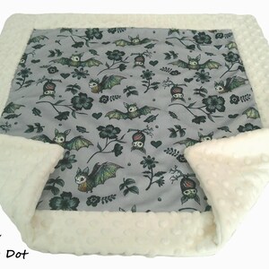 May include: A square blanket featuring a central gray panel with a repeating pattern of bats, flowers, and hearts. The blanket is bordered by a textured cream-colored minky dot fabric. The text Cream Minky Dot is visible in the bottom left corner.