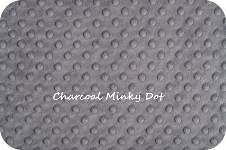 May include: A charcoal gray fabric featuring a raised, embossed dot pattern across the entire surface. The text 'Charcoal Minky Dot' is printed in white in the center of the fabric, which has rounded corners and a soft, textured appearance.