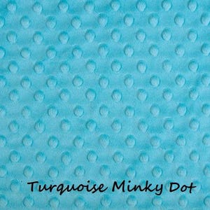 May include: A turquoise minky fabric featuring a raised, embossed dot pattern across the entire surface. The text "Turquoise Minky Dot" is printed in black, sans-serif lettering at the bottom center of the fabric material.