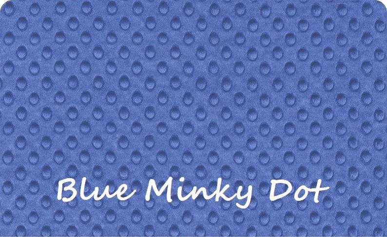 May include: A blue minky fabric featuring a raised, embossed dot pattern across the entire surface. The text "Blue Minky Dot" is printed in white, cursive lettering across the lower portion of the fabric, which has a soft, textured appearance.
