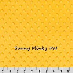 Pu&ograve; includere: Tessuto giallo con un motivo a pois strutturato. Le parole "Sunny Minky Dot" sono stampate sul tessuto. Un righello &egrave; nella parte inferiore dell'immagine, con misure in centimetri.