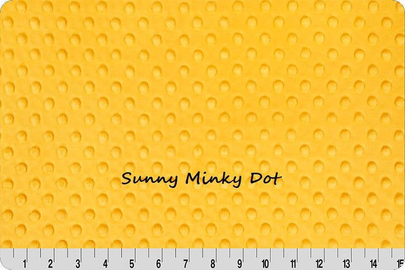Pu&ograve; includere: Tessuto giallo con un motivo a pois strutturato. Le parole "Sunny Minky Dot" sono stampate sul tessuto. Un righello &egrave; nella parte inferiore dell'immagine, con misure in centimetri.
