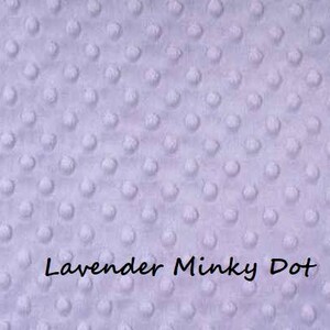 Puede incluir: Primer plano de una tela de punto minky lavanda. La tela tiene una textura suave y afelpada con peque&ntilde;os puntos en relieve.