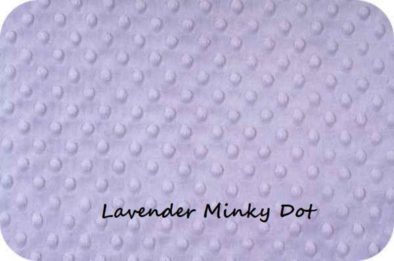 Puede incluir: Primer plano de una tela de punto minky lavanda. La tela tiene una textura suave y afelpada con peque&ntilde;os puntos en relieve.