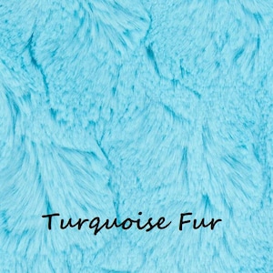 May include: A vibrant turquoise faux fur fabric with a dense, soft, and shaggy texture. The surface features long, flowing synthetic fibers in varying shades of bright blue and cyan. The text "Turquoise Fur" is printed in black in the center.