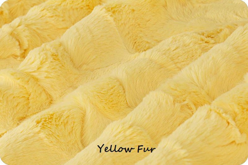 May include: Close-up of a soft, yellow faux fur fabric. The fur is fluffy and has a wavy texture. The text "Yellow Fur" is printed at the bottom of the image.
