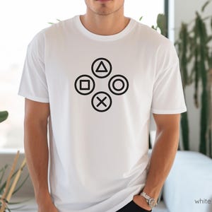 May include: White t-shirt with a black graphic of the PlayStation controller buttons.