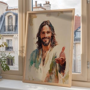May include: A framed print of a smiling man with long brown hair and a beard, wearing a white and blue robe. The artwork is displayed on a windowsill, with a view of buildings and a plant in the background.