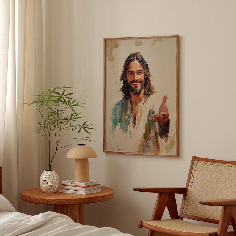 May include: A framed portrait of a smiling person with long brown hair and a beard, wearing a white and blue robe. The artwork is in a wooden frame and hangs on a beige wall. The room also features a wooden side table, a lamp, and a chair.