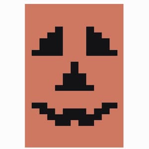 May include: A rectangular orange graphic print featuring a black pixelated jack-o'-lantern face. The design consists of two triangular eyes, a central triangular nose, and a wide, jagged mouth, all rendered in a distinct blocky, digital style.