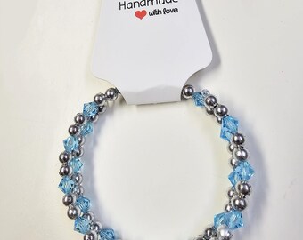 May include: A silver and light blue beaded bracelet with a white tag that reads "Handmade with love".