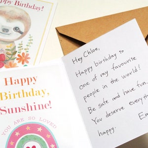 Op de afbeelding: Een wenskaart met een aquarelillustratie van een luiaard met bloemen, de tekst Happy Birthday, Sunshine, You are so loved en een regenboog. De binnenkant bevat een handgeschreven bericht aan Chloe, inclusief een bruine envelop.