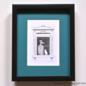 Może przedstawiać: Czarna oprawiona grafika z ilustracją pi&oacute;rem i tuszem. Grafika przedstawia postać w oknie z kotem. Postać ma na sobie kapelusz i płaszcz. Grafika jest oprawiona w czarną ramę z zieloną matą.