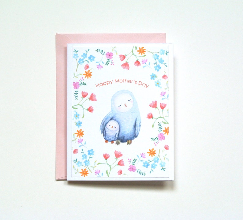 A baby owl is snuggling to it's mom, and mother is holding the baby under her wing.  They are surrounded by pretty small flowers.  The card says; Happy Mother's Day