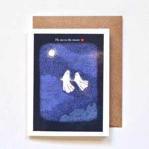 Two ghosts are flying in the night sky with a full moon.  The card says; Fly me to the moon