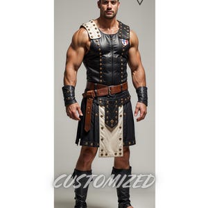 May include: A black leather kilt with white accents and gold studs. The kilt is paired with a black leather vest with gold studs and a brown leather belt. The model is wearing black leather arm bands and black leather leg bands.
