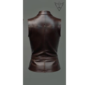 May include: A brown leather vest with a collar, a belt, and a button closure. The vest is sleeveless and has a fitted silhouette.