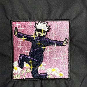 May include: Embroidered patch featuring a cartoon character with white hair, wearing a dark blue shirt and purple pants, standing in a pink background with white daisies and yellow stars.
