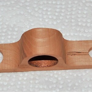 May include: A wooden shelf with two round holes and a larger, rounded cutout in the center. The shelf is light brown and has a natural wood grain.