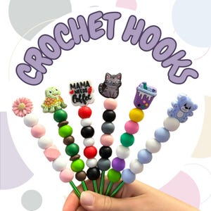 May include: A selection of crochet hooks with various decorative toppers, such as a turtle and a cat. The hooks feature colourful beads and the text "CROCHET HOOKS" is displayed above them.