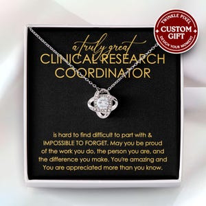 May include: A silver necklace with a pendant featuring a central clear stone surrounded by smaller stones. The necklace is presented in a gift box with text that reads "a truly great CLINICAL RESEARCH COORDINATOR". A custom gift label is also visible.