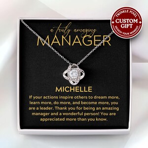 Peut inclure: Un collier argenté avec un pendentif orné d'une pierre centrale transparente entourée de petites pierres. Le coffret cadeau contient les mots "a truly amazing MANAGER" et "MICHELLE", ainsi qu'un message de remerciement.