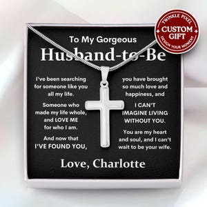 May include: A silver cross pendant necklace presented in a gift box. The box features a message to a husband-to-be, with the words "To My Gorgeous Husband-to-Be" at the top. The necklace is a sentimental gift.