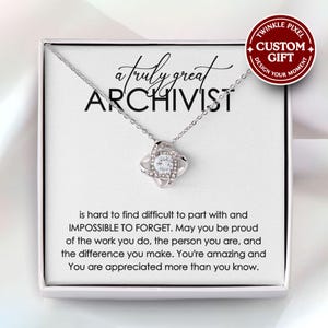 May include: A silver necklace with a knot-shaped pendant, adorned with clear crystals. The necklace is displayed in a white gift box, with the words "a truly great ARCHIVIST" and a message. A red circle says "CUSTOM GIFT".