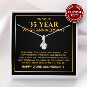 May include: A silver necklace with a pendant in a gift box. The box has a black background with gold text that reads "ON YOUR 35 YEAR WORK ANNIVERSARY." The text "HAPPY WORK ANNIVERSARY!" is also visible.