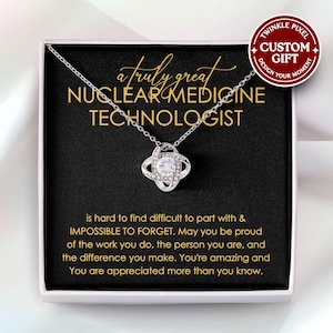 Op de afbeelding: Een zilveren ketting met een kristallen knoop hanger wordt geleverd in een zwarte geschenkdoos met een boodschap die luidt: "a truly great NUCLEAR MEDICINE TECHNOLOGIST is hard to find difficult to part with & IMPOSSIBLE TO FORGET. May you be proud of the work you do, the person you are, and the difference you make. You're amazing and You are appreciated more than you know."