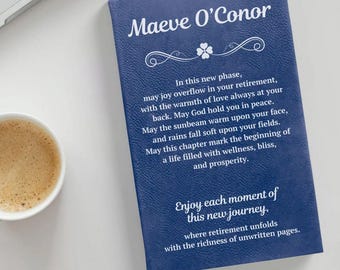 May include: A navy blue journal with the name "Maeve O'Conor" in white script. The journal includes an inspirational message about retirement. A cup of coffee sits to the left of the journal.