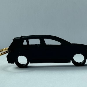 Può includere: Un portachiavi per auto nero con un anello dorato. Il portachiavi è una silhouette di un'auto con un design dettagliato.