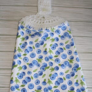 May include: A white crocheted dish towel holder with a blue and white blueberry print. The holder has a loop at the top for hanging.