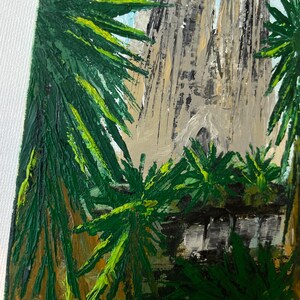 May include: An oil painting depicts the Sagrada Familia basilica in Barcelona, Spain. The artwork features the church's spires and facade, framed by green palm fronds. The sky is a light blue, and the painting has a textured, impressionistic style.