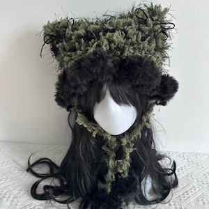 Puede incluir: Tocado artesanal con una combinaci&oacute;n de texturas y colores. Presenta un borde afelpado marr&oacute;n oscuro, una corona texturizada verde oliva y detalles en negro. Un accesorio &uacute;nico y llamativo.