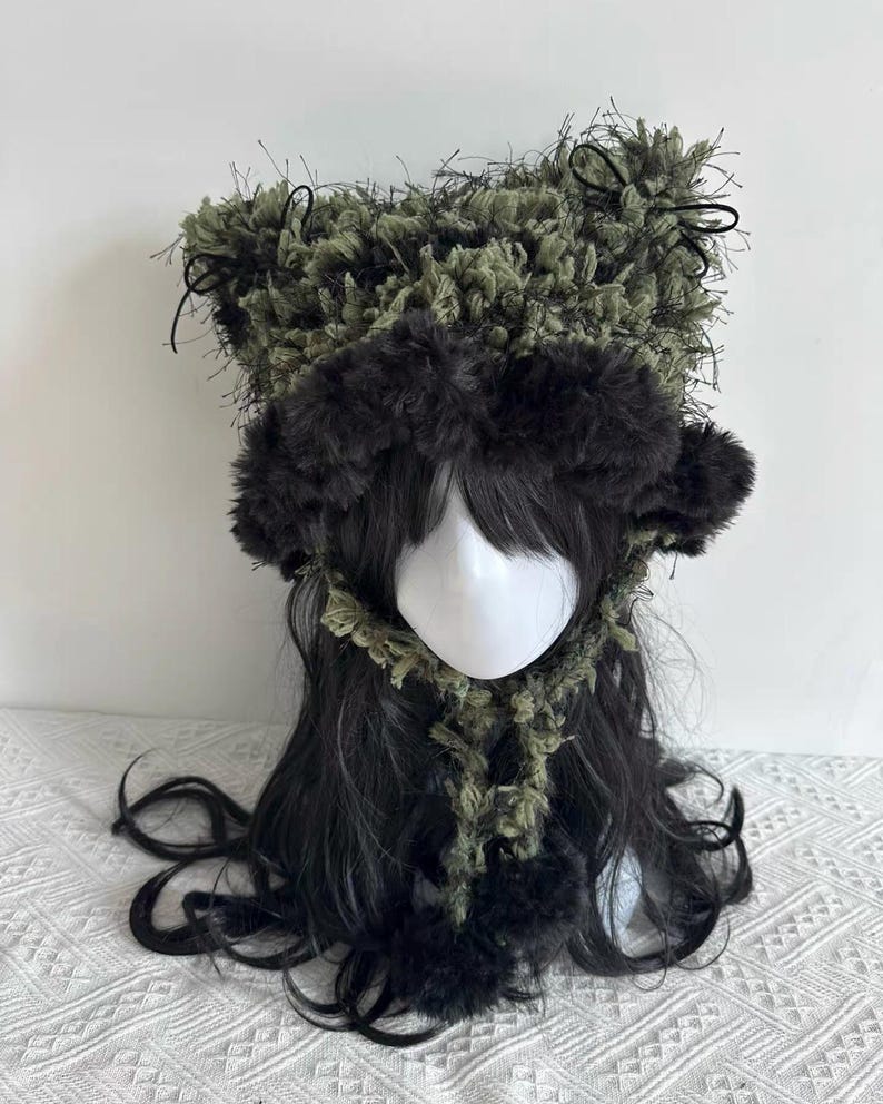 Puede incluir: Tocado artesanal con una combinaci&oacute;n de texturas y colores. Presenta un borde afelpado marr&oacute;n oscuro, una corona texturizada verde oliva y detalles en negro. Un accesorio &uacute;nico y llamativo.