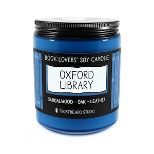 May include: A blue soy candle in a glass jar with a black lid. The label reads "Oxford Library" with scent notes of sandalwood, oak, and leather. The text "Book Lovers' Soy Candle" is also on the label.