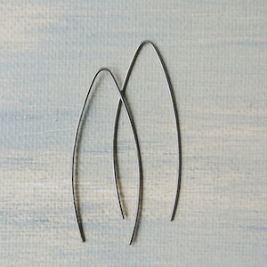 Op de afbeelding: Een paar zilveren ovale oorbellen. De oorbellen zijn gemaakt van dunne draad en zijn ongeveer 5 cm lang.