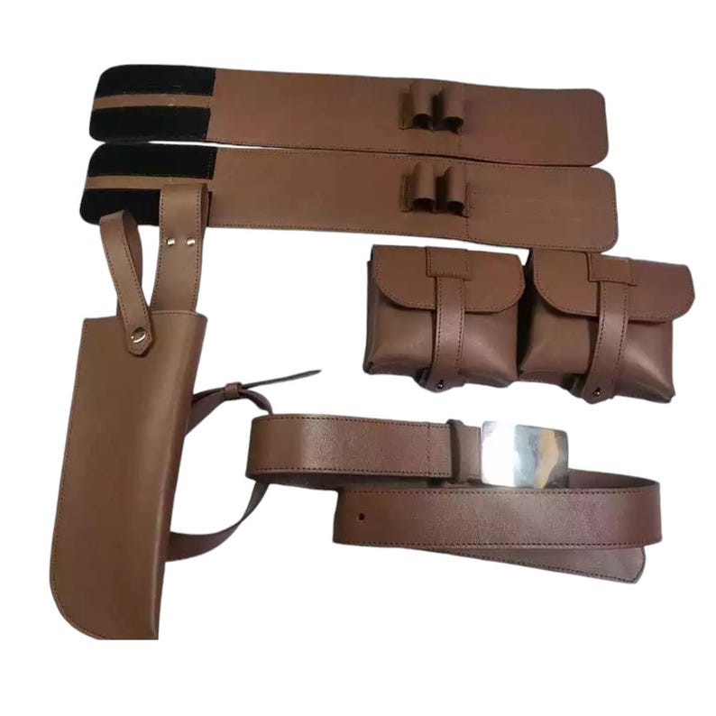 May include: A brown leather belt with a silver buckle and two brown leather pouches. The belt has a brown leather holster attached to it.