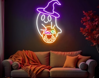 May include: A neon sign in the shape of a ghost wearing a witch hat, holding a jack-o'-lantern. The sign is outlined in white, purple, and orange, and is mounted on a dark wall. A sofa with orange pillows and a blanket is below the sign.