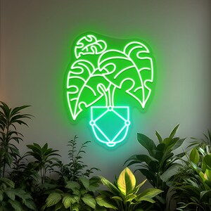 May include: A neon green sign depicting a potted plant with large leaves. The sign is mounted on a light green wall, surrounded by various green plants.