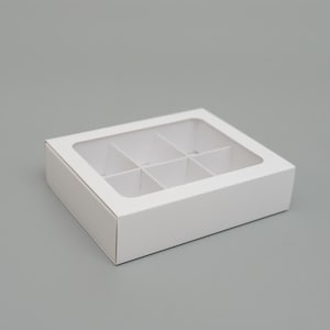 Peut inclure: Une boîte rectangulaire en carton blanc dotée d'une fenêtre transparente sur le couvercle. L'intérieur de la boîte est divisé en six compartiments carrés égaux par des inserts en carton blanc, offrant un espace de rangement organisé.